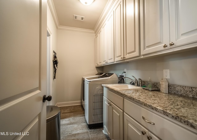 laundry area with cabinets, washer and dryer, crown molding, and sink