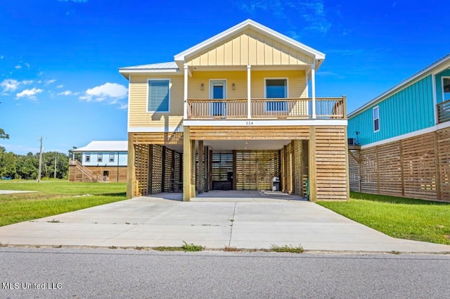 coastal home featuring a front yard, covered porch, and a carport