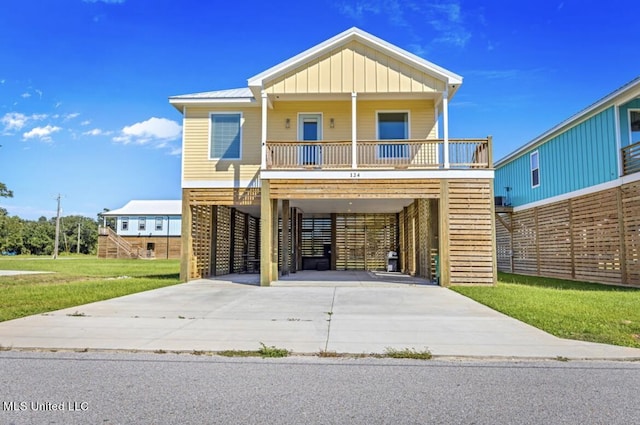 coastal home with board and batten siding, a porch, driveway, a front yard, and a carport