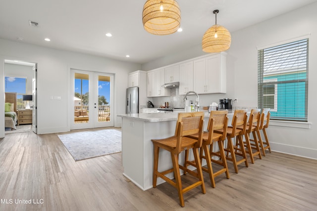 kitchen featuring light hardwood / wood-style flooring, kitchen peninsula, white cabinetry, and pendant lighting