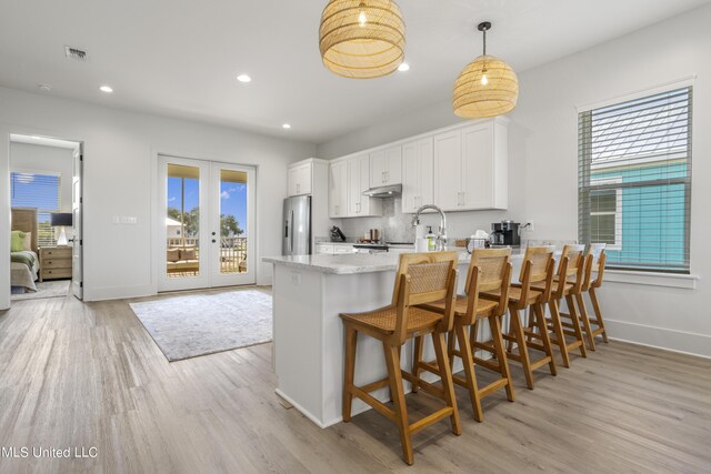 124 Arkansas Ave, Gulfport, MS 39507 - kitchen with white cabinets, a peninsula, baseboards, and light wood finished floors