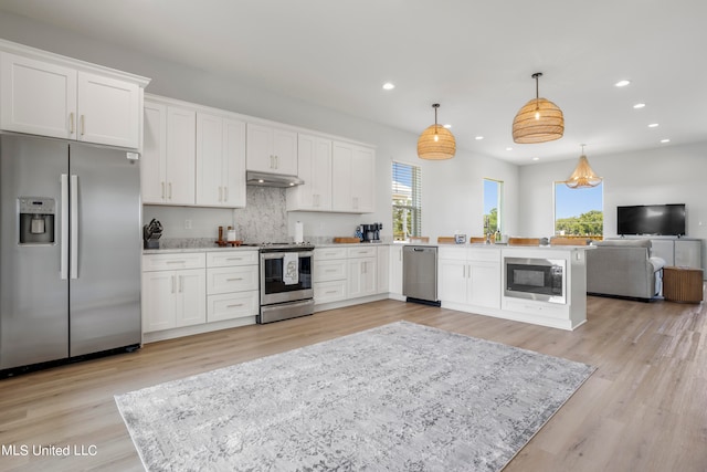 kitchen with appliances with stainless steel finishes, decorative light fixtures, plenty of natural light, and white cabinets