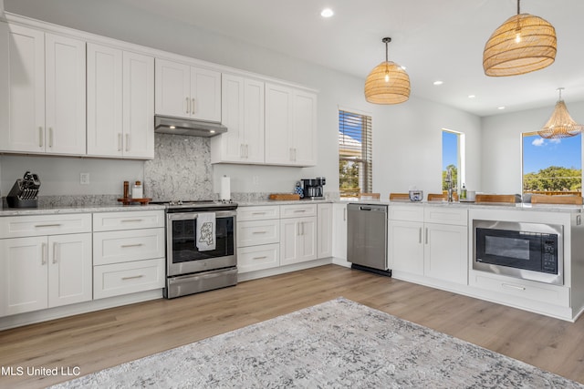 kitchen featuring appliances with stainless steel finishes, decorative light fixtures, and white cabinetry