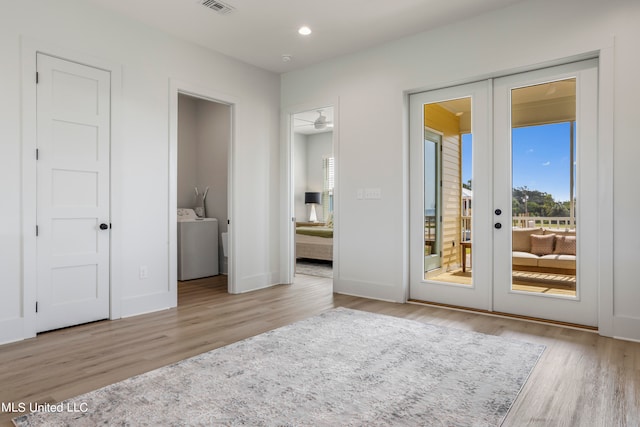 unfurnished bedroom featuring french doors, access to exterior, washer / dryer, light hardwood / wood-style flooring, and ensuite bath