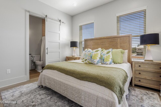 124 Arkansas Ave, Gulfport, MS 39507 - bedroom featuring baseboards, ensuite bath, a barn door, and wood finished floors