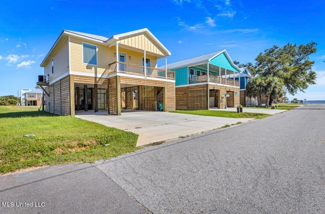 view of front facade with a carport, a balcony, and a front lawn