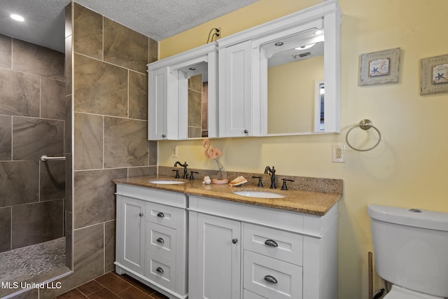 full bathroom with a textured ceiling, walk in shower, a sink, and toilet