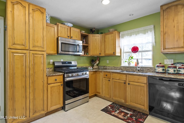 kitchen with brown cabinetry, dark stone counters, appliances with stainless steel finishes, open shelves, and a sink