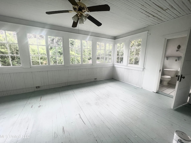 unfurnished sunroom featuring ceiling fan and a wealth of natural light