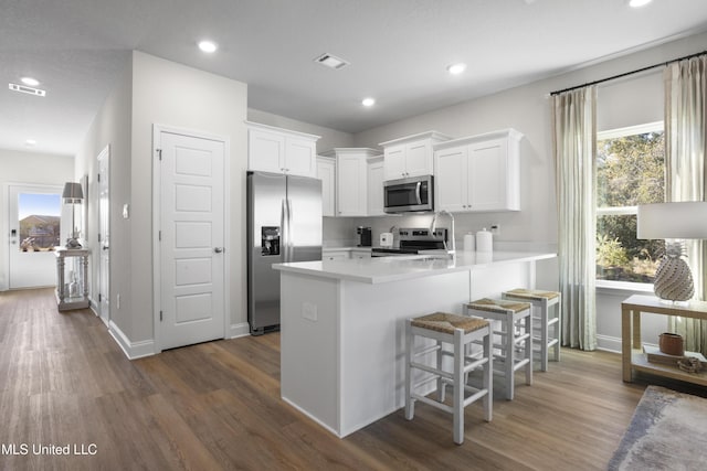 12278 Frazier Ln, Gulfport, MS 39503 - kitchen with stainless steel appliances, a peninsula, dark wood finished floors, white cabinets, and recessed lighting