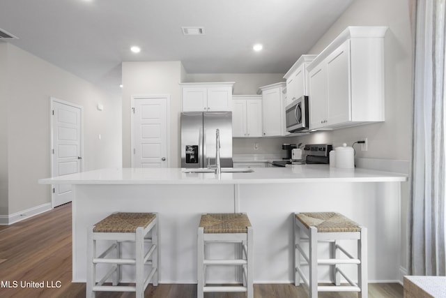 12278 Frazier Ln, Gulfport, MS 39503 - kitchen featuring stainless steel appliances, white cabinetry, a peninsula, a breakfast bar, and light countertops