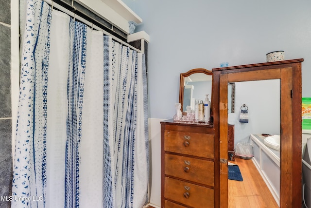 221 S Third St, Wiggins, MS 39577 - bathroom featuring wood finished floors, curtained shower, and a bath