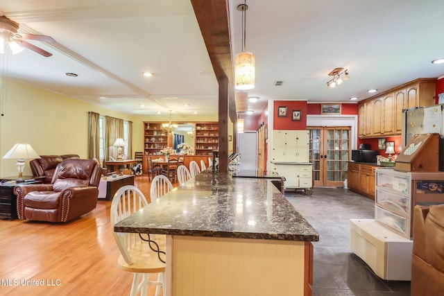 221 S Third St, Wiggins, MS 39577 - kitchen with a ceiling fan, open floor plan, a kitchen bar, freestanding refrigerator, and dark stone counters