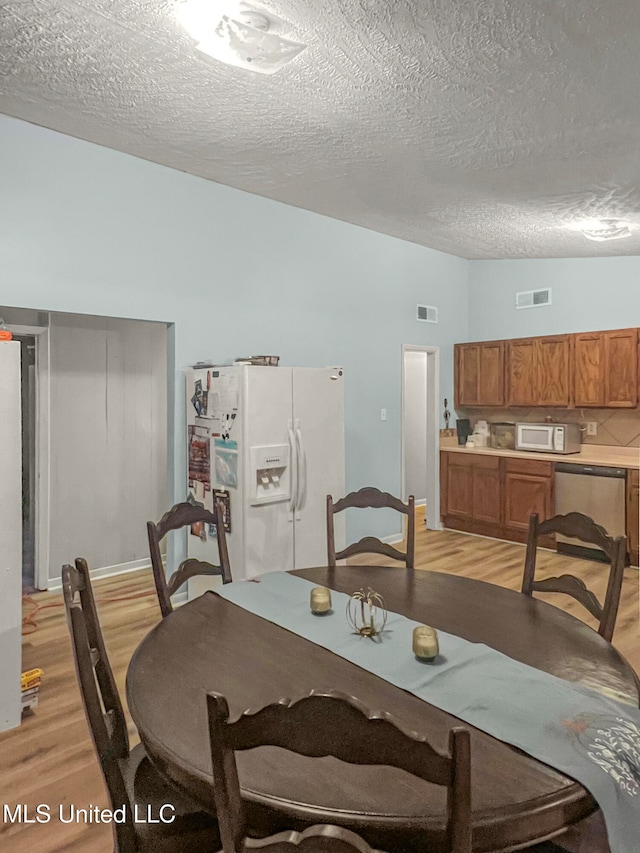 dining area with light hardwood / wood-style floors and a textured ceiling