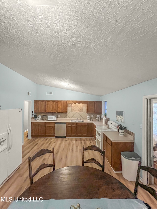 kitchen featuring sink, white appliances, a textured ceiling, and light hardwood / wood-style floors