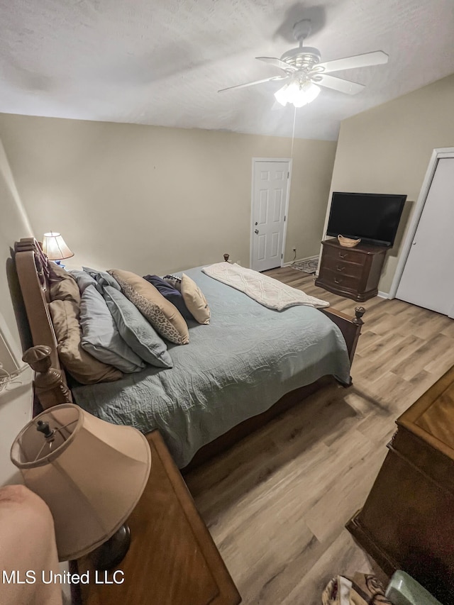 bedroom with ceiling fan, a textured ceiling, and light hardwood / wood-style flooring