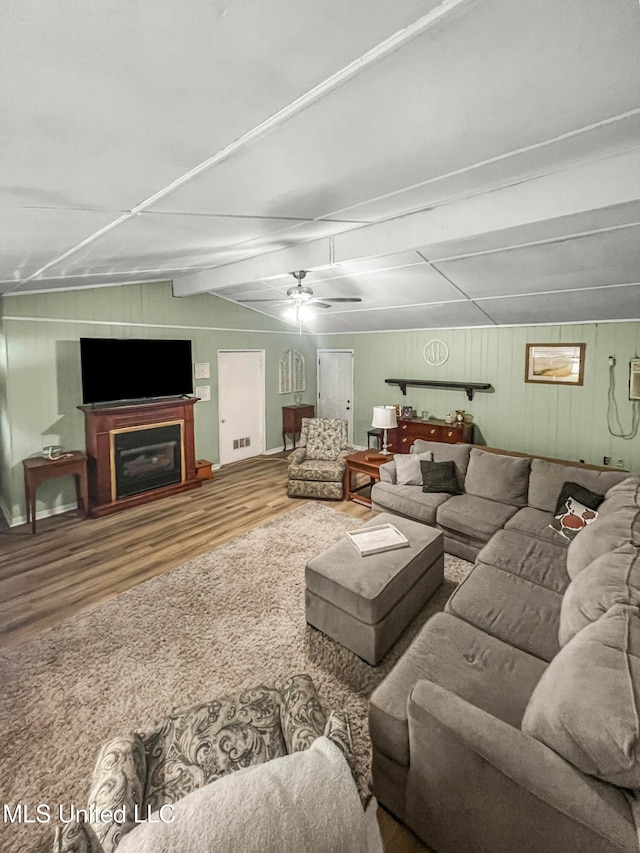 living room with lofted ceiling with beams, wooden walls, hardwood / wood-style flooring, and ceiling fan