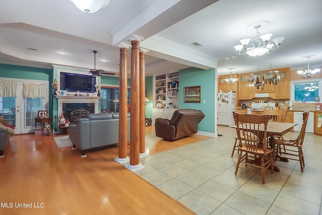 dining space with ceiling fan, light wood-type flooring, ornamental molding, ornate columns, and built in shelves