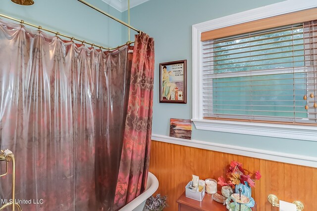 bathroom with wood walls, a shower with shower curtain, and a wainscoted wall