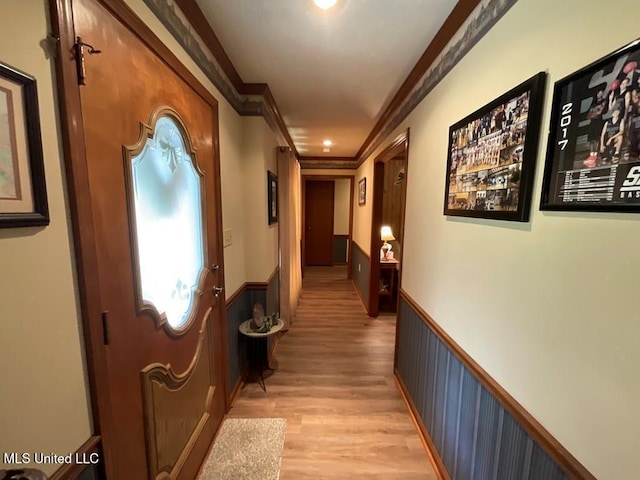 hallway featuring light wood-type flooring and ornamental molding