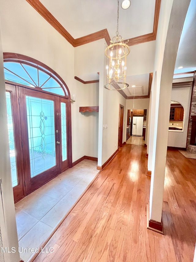 entrance foyer with light hardwood / wood-style flooring, a notable chandelier, crown molding, and a wealth of natural light