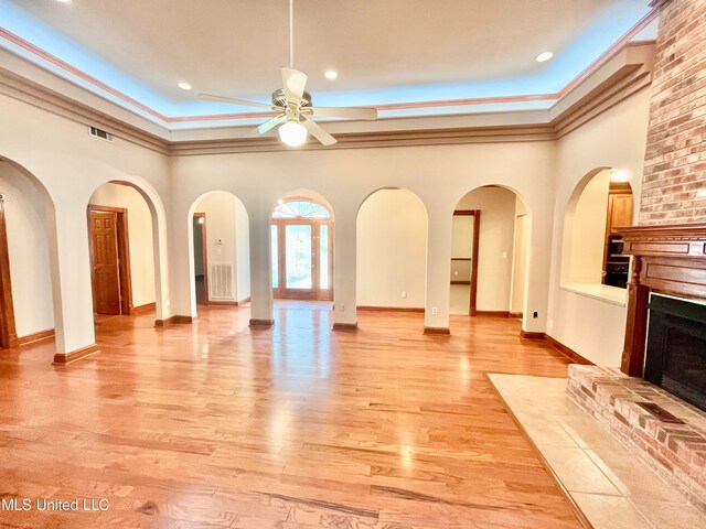 unfurnished living room featuring crown molding, light hardwood / wood-style flooring, a fireplace, and ceiling fan