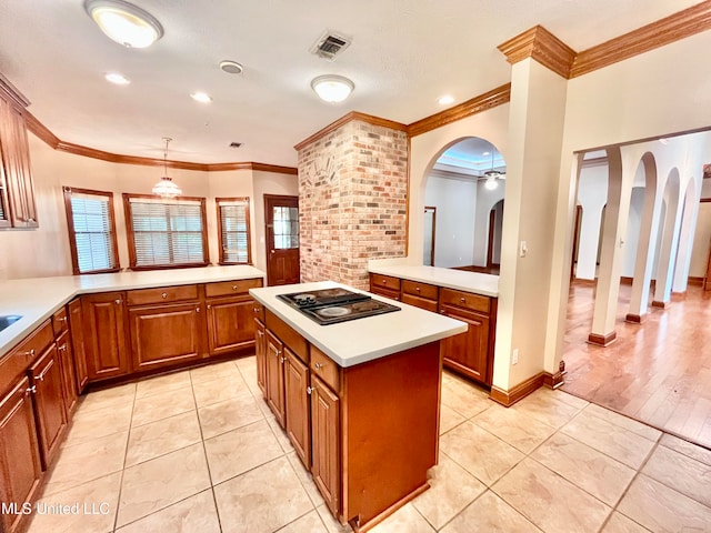 kitchen featuring hanging light fixtures, black electric stovetop, light hardwood / wood-style floors, crown molding, and a center island