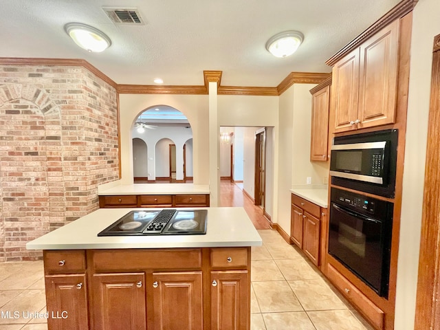 kitchen featuring a kitchen island, light tile patterned flooring, black appliances, crown molding, and brick wall