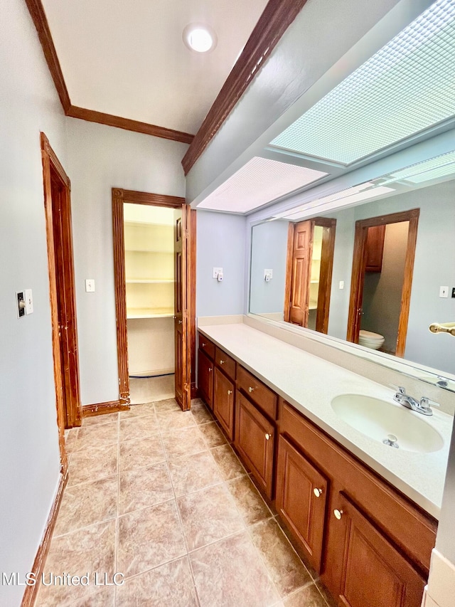 bathroom with toilet, ornamental molding, vanity, and tile patterned floors