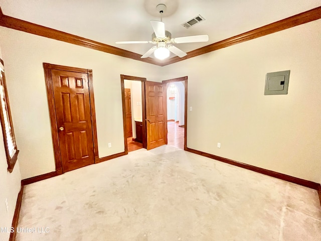 unfurnished bedroom featuring electric panel, ceiling fan, crown molding, ensuite bath, and light colored carpet