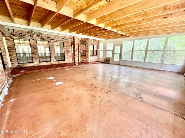 unfurnished living room featuring brick wall