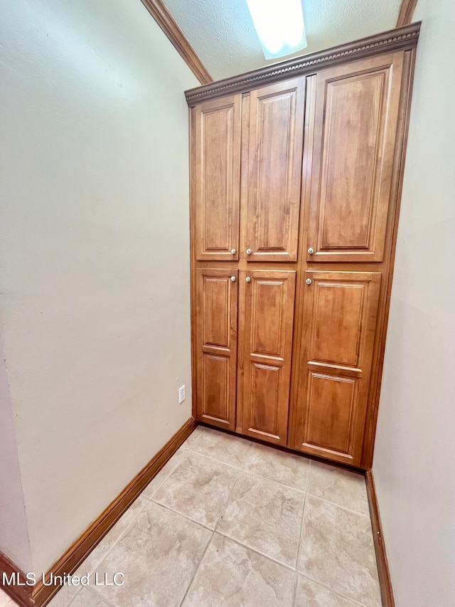 interior details with ornamental molding, a textured ceiling, and tile patterned floors