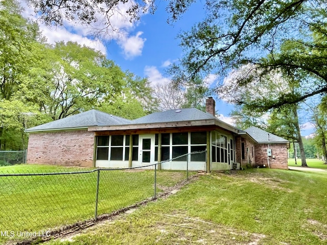 rear view of property with a yard and a sunroom