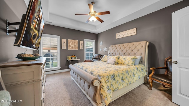 carpeted bedroom featuring a tray ceiling and ceiling fan