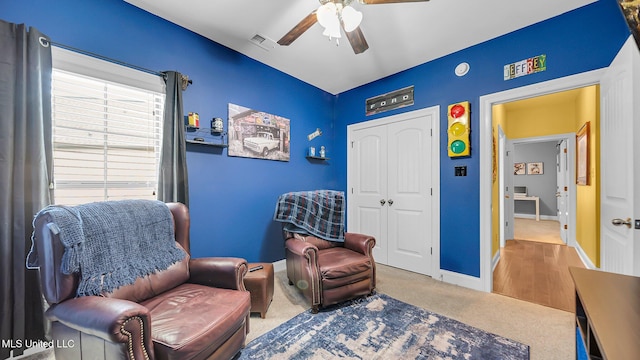 living area featuring carpet flooring and ceiling fan