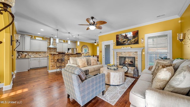 living room featuring ceiling fan, a fireplace, ornamental molding, and dark hardwood / wood-style floors