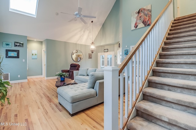 living room featuring ceiling fan with notable chandelier, high vaulted ceiling, light hardwood / wood-style flooring, and a wealth of natural light