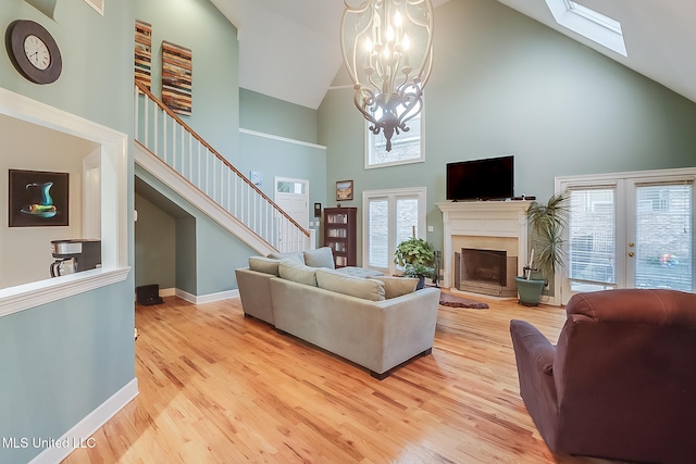 living room with light hardwood / wood-style flooring, high vaulted ceiling, a chandelier, and french doors