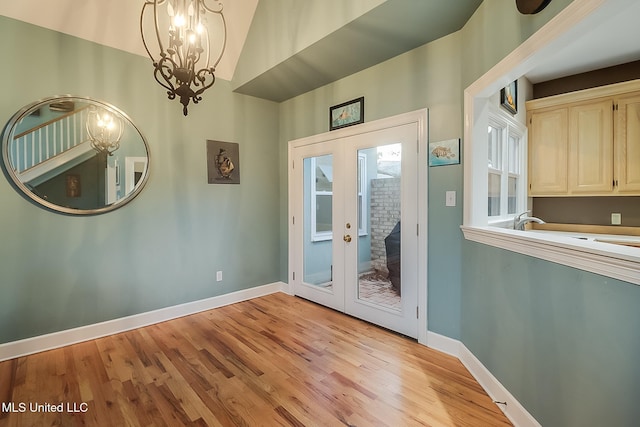 doorway to outside with french doors, light hardwood / wood-style floors, and an inviting chandelier