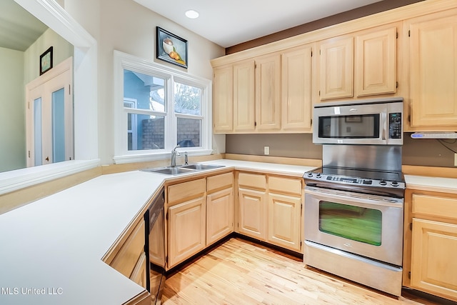 kitchen with appliances with stainless steel finishes, light hardwood / wood-style floors, light brown cabinetry, and sink