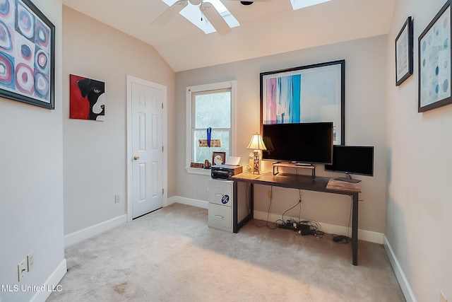 office space featuring ceiling fan, vaulted ceiling with skylight, and light carpet