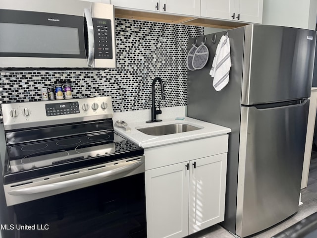 kitchen with tasteful backsplash, appliances with stainless steel finishes, sink, and white cabinets