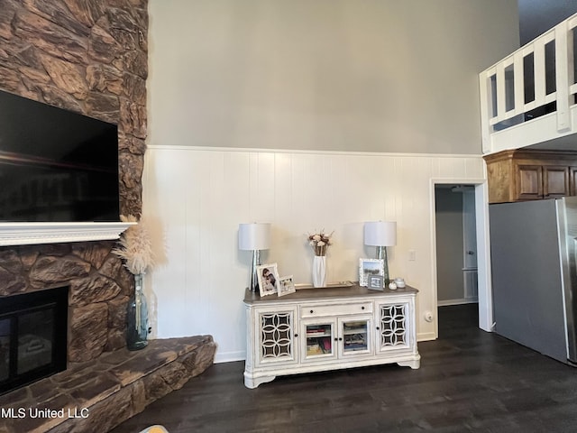 living room with dark wood-type flooring, a high ceiling, and a fireplace