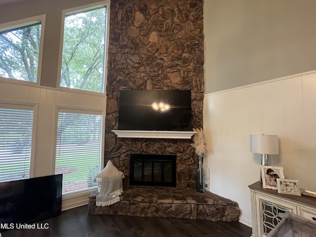 living room with hardwood / wood-style floors, a stone fireplace, and a towering ceiling