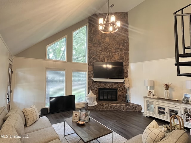 living room featuring high vaulted ceiling, a fireplace, wood-type flooring, and an inviting chandelier