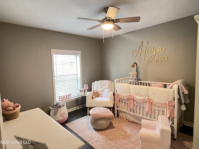 bedroom featuring a nursery area and ceiling fan