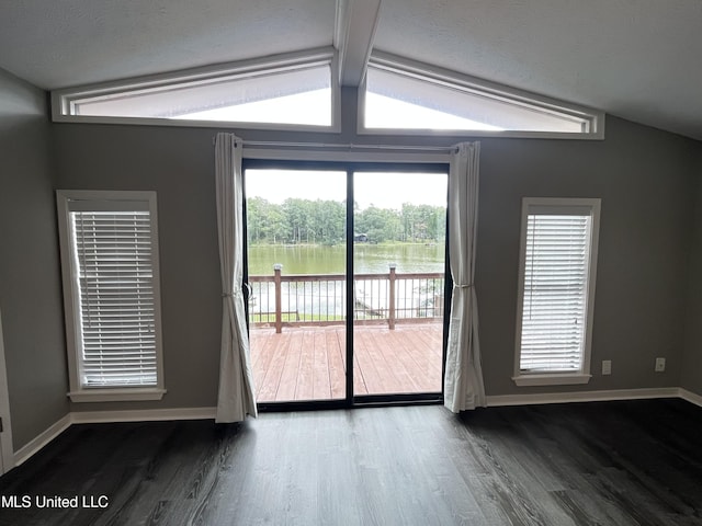 empty room featuring lofted ceiling with beams, dark wood-type flooring, and a water view