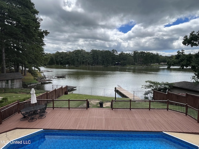 view of pool featuring a deck with water view and a lawn