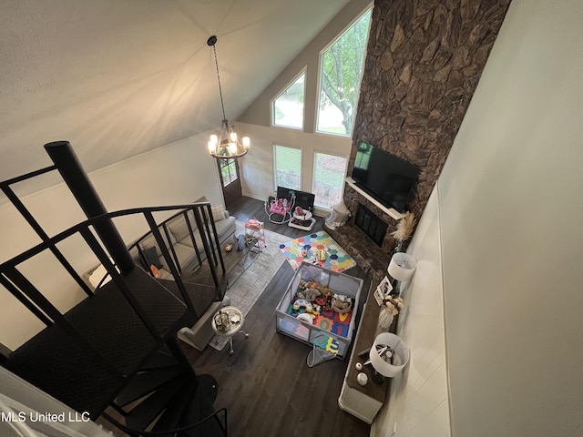 living room with a stone fireplace, a chandelier, high vaulted ceiling, and wood-type flooring