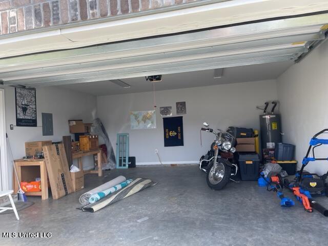 garage featuring secured water heater, a garage door opener, and electric panel